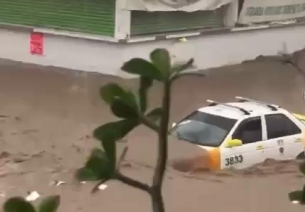 Corriente arrastra un taxi en Acapulco.