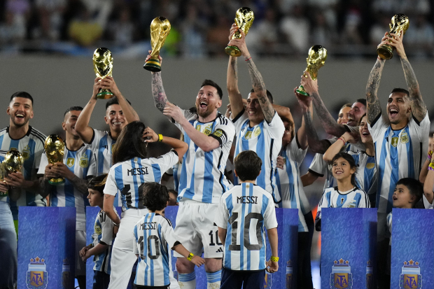 Lionel Messi y otros futbolistas de Argentina sostienen réplicas de la Copa Mundial de la FIFA que conquistaron en Qatar, después de su triunfo ante Panamá en Buenos Aires.