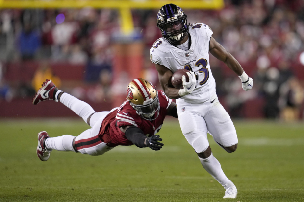 El corredor de los Baltimore Ravens Justice Hill corre con el balón frente al linebacker de los San Francisco 49ers Demetrius Flannigan-Fowles en la NFL