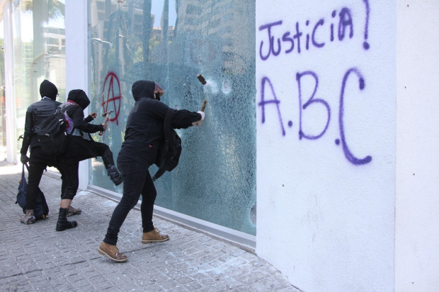 Encapuchadas destrozan un vidrio con martillos, en inmediaciones de la embajada de Estados Unidos en la Ciudad de México, durante la protesta del viernes anterior.