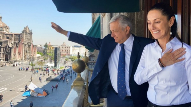 El Presidente López Obrador y Claudia Sheinbaum se asoman por un balcón del Palacio Nacional
