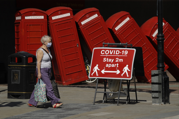Una mujer camina frente a una escultura de cabinas del artista David Mach, ayer, en Londres