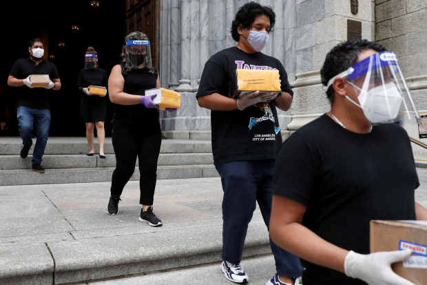 Personas salen de un servicio religioso en la Catedral de San Patricio, en Nueva York. Cargan urnas con cenizas de muertos por coronavirus.
