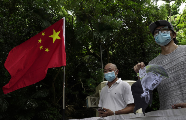 Partidarios pro-China protestan a las afueras de la embajada de EU en Hong Kong, el sábado pasado, con una caricatura del presidente Trump luego de que Washington impuso sanciones a funcionarios de ese país cuando las acusaciones mutuas van en aumento.
