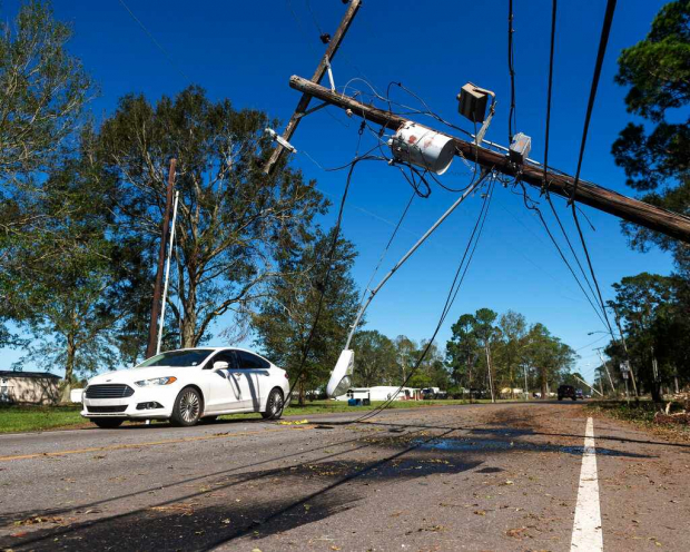 Un vehículo pasa por un poste de electricidad dañado después de que el huracán Delta pasara por el área cerca de Lake Arthur, Luisiana