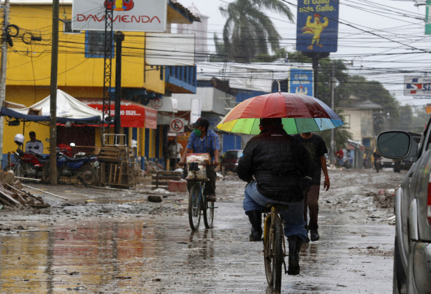 Lugareños transitan ayer por los escombros que dejó la última tormenta en La Lima, Honduras.