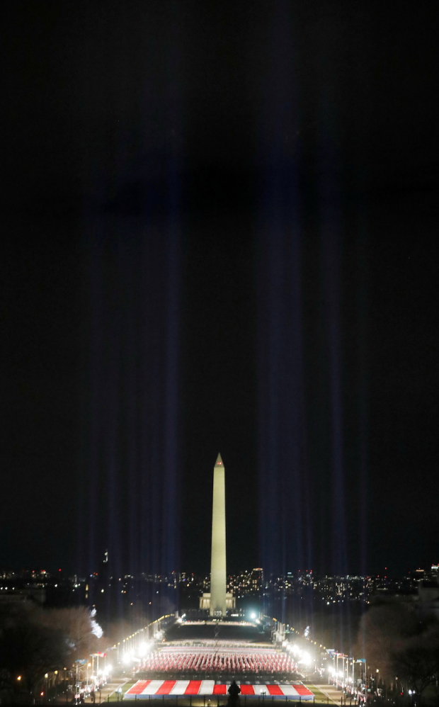 Luces iluminan el monumento a Washington desde el “campo de banderas” en el National Mall.
