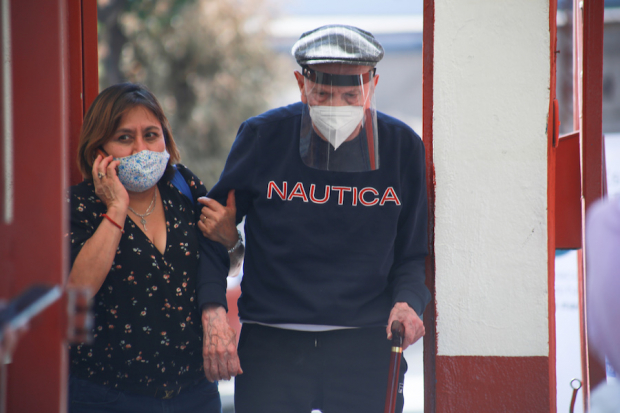 Una mujer acompaña a su padre al punto de vacunación en Magdalena Contreras.