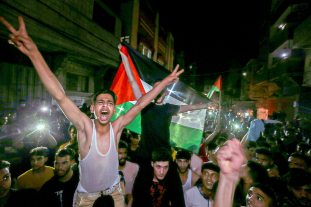 Con banderas y sin cubrebocas palestinos celebran el fin de las hostilidades en Gaza, ayer.
