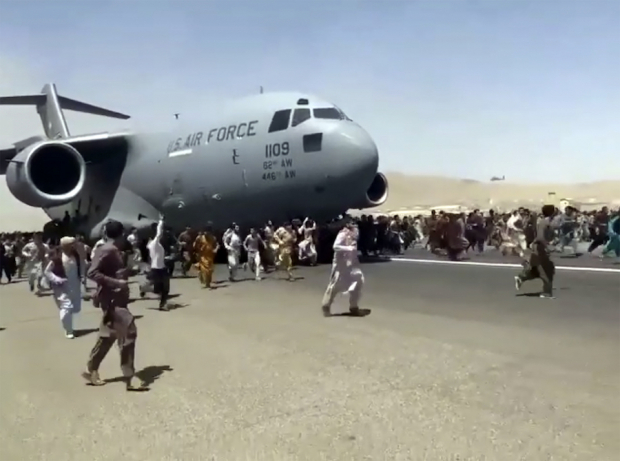 Cientos de personas, en su mayoría hombres, corren tras un avión militar de EU
que salía de Afganistán, luego de que los talibanes tomaran la capital Kabul, el lunes.