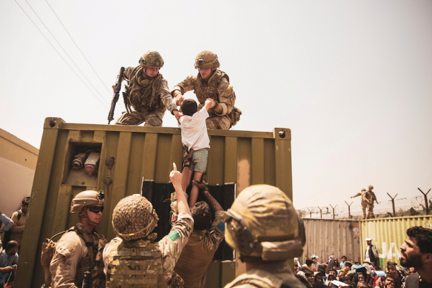 Marines de EU ayudan a un niño durante el desalojo en Kabul, ayer.