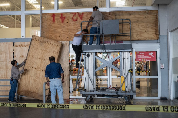 Trabajadores tapan con madera las ventanas de un establecimiento en el puerto de Veracruz, ayer, ante la inminente llegada del fenómeno meteorológico.