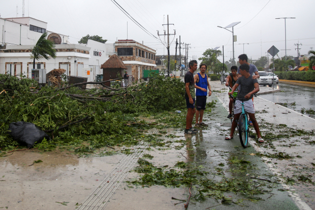 La gente se reúne cerca de árboles caídos después de que el huracán Grace tocó tierra en la península de Yucatán, en Tulum