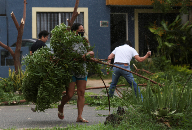 Una mujer borra las ramas rotas de los árboles después de que el huracán Grace tocara tierra en la península de Yucatán, en Mérida.