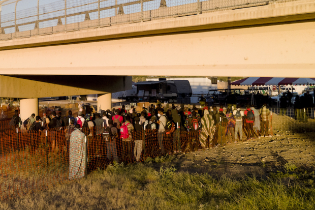 Migrantes hacen fila para subir a los autobuses en Texas, ayer.