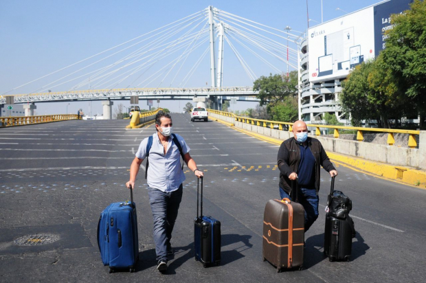 Turistas transitan a pie para acceder a la Terminal 1 del AICM, debido al bloqueo vehicular.