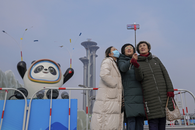 Mujeres en China posan para una foto ante la mascota de los Juegos Olímpicos de Invierno de Beijing, ayer.