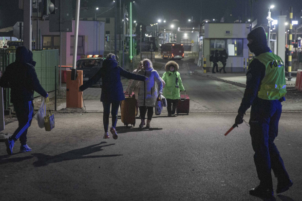 Ciudadanos caminan con sus pertenencias en una maleta hasta la frontera con Polonia.