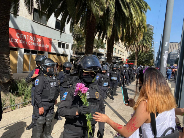 Mujer entrega flores a una policía de la SSC.