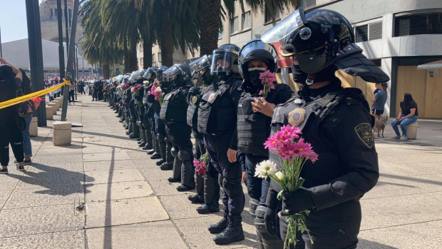 Mujeres policías sostiene ramos de flores que les entregaron activistas e integrantes de colectivos feministas que participan en las movilizaciones por el 8M-