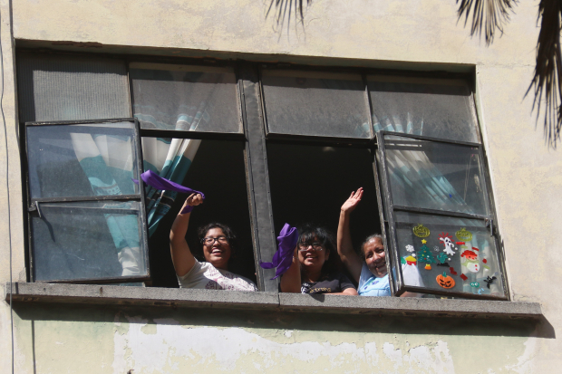 Mujeres saludan desde una ventana al contingente.