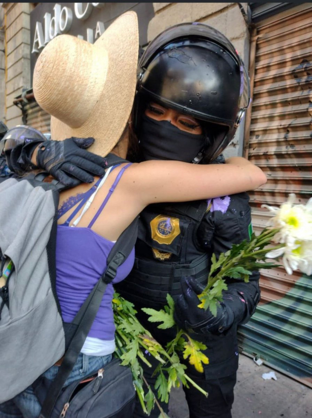 Una mujer entrega una flor y abraza a una policía capitalina, ayer.