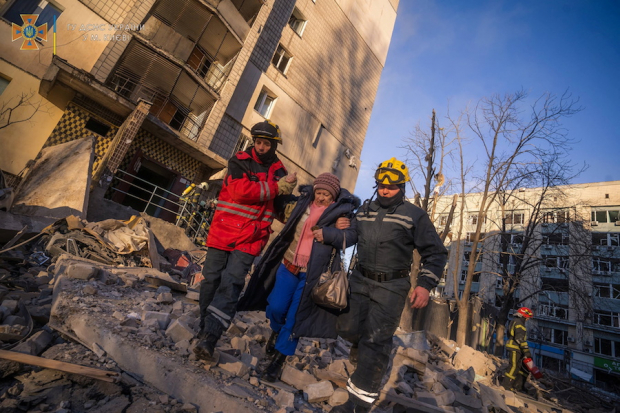 Rescatistas ayudan a una mujer a evacuar un edificio residencial dañado por  bombarderos rusos, en Kiev, ayer.