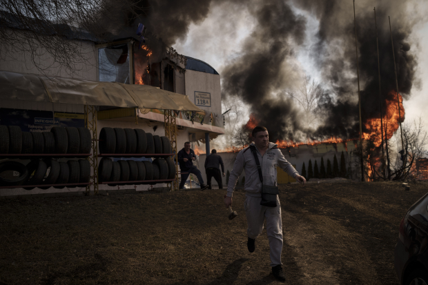 Personas intentan recuperar artículos de una tienda en llamas en Kharkiv tras un ataque ruso, ayer.
