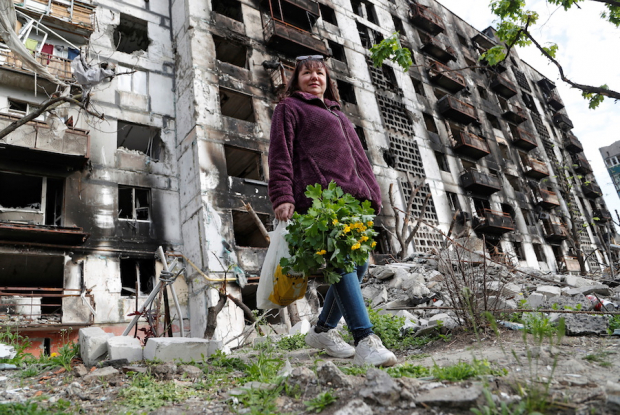 Ucraniana camina frente a edificios prácticamente destruidos.