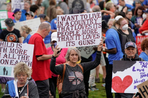 Mujer con una cartel que dice "Quiero vivir en una país que ame a su gente más que de lo que ama a sus armas".