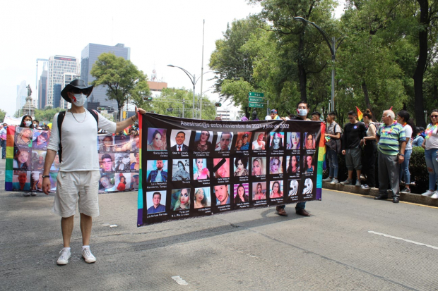 Manifestantes llevan lonas de personas integrantes de la comunidad LGBTIQ+ que fueron víctimas de crímenes de odio contra la diversidad sexual.