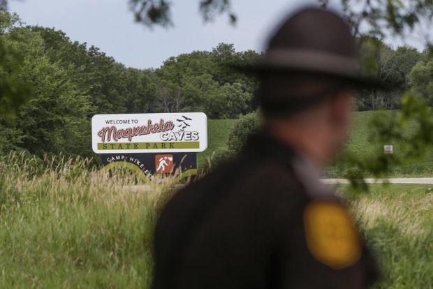 Un patrullero estatal de Iowa pasa junto a un letrero del Parque Estatal Maquoketa Caves.