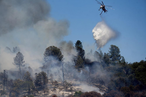 Un helicóptero arroja agua sobre el incendio "Oak".