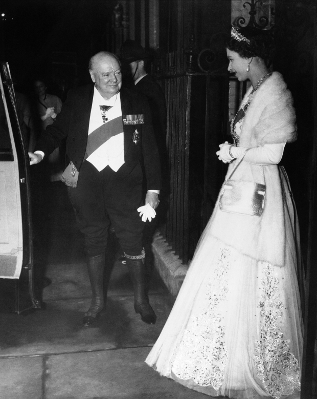 El primer ministro británico Sir Winston Churchill, vestido de gala, abre la puerta de un auto para la reina Isabel II tras una cena de despedida para el primer ministro en la residencia oficial de Downing Street, en Londres el 5 de abril de 1955.
