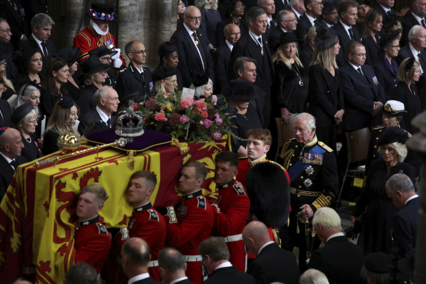 El ataúd de la monarca británica es cargado por guardias para su funeral, en Londres, mientras son seguidos por el rey Carlos III, ante invitados especiales, ayer.