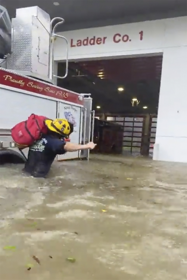 Bombero camina en una estación inundada por las fuertes lluvias.