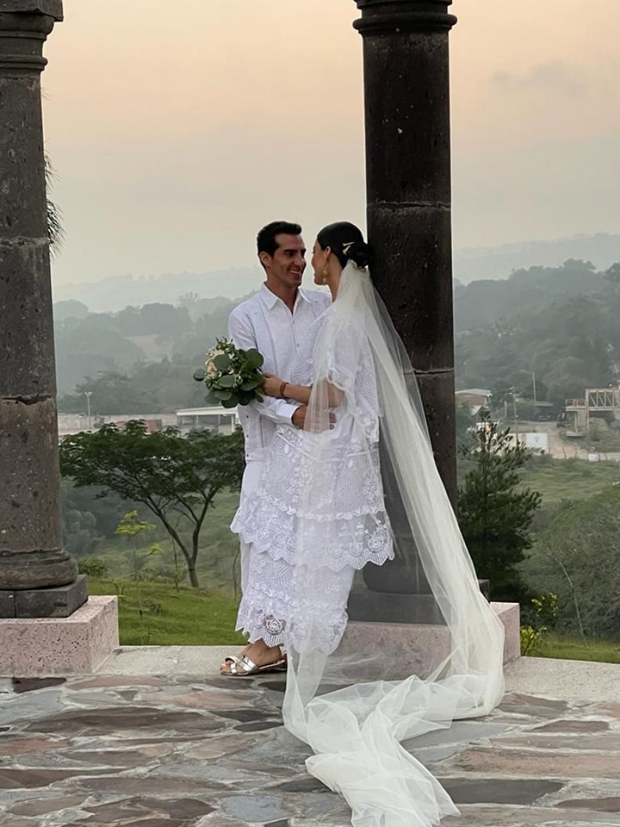 La novia portó un huipil blanco con un velo largo y sandalias plateadas; y el novió portó una filipina blanca y un pantalón en el mismo tono.