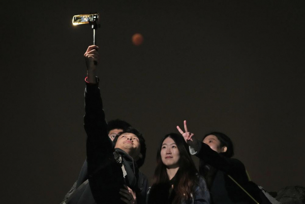Un grupo de personas se toma un selfie durante el eclipse lunar en Beijing, China, el 8 de noviembre del 2022.