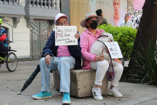 Manifestantes descansan de la marcha con pancartas en mano.