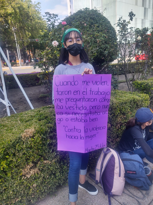 Una joven posa con un cartel con el cual protesta contra la violencia hacia la mujer.
