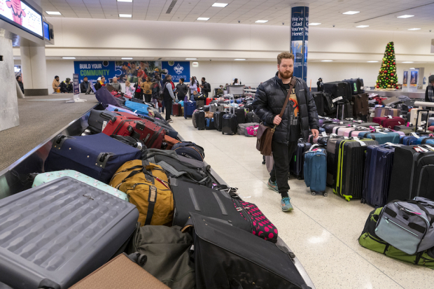 Pasajeros aguardan entre maletas a que el aeropuerto de Chicago reanude actividades.