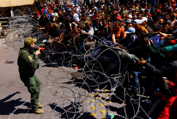 Un agente fronterizo de Estados Unidos pide a los migrantes que se alejen del alambrado,
el pasado domingo 12 de marzo, en el puente interncional Paso del Norte-Santa Fe.