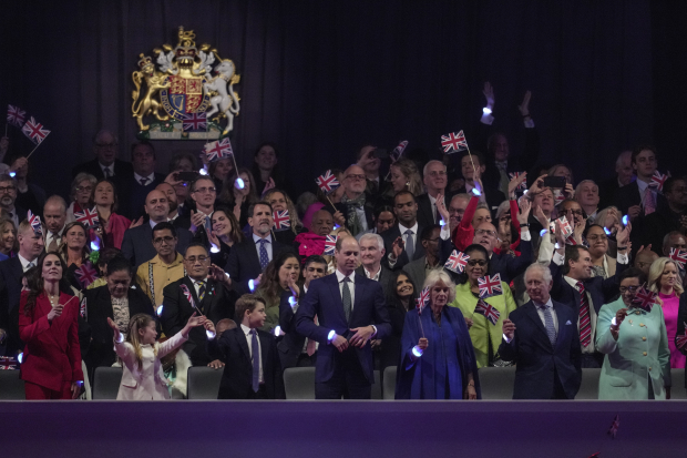 El rey Carlos III y su esposa Camila Parker  ondean banderines de GB durante el concierto, junto a la familia real en primera fila.
