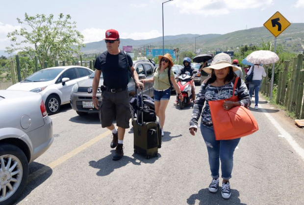 Turistas debieron caminar ayer para llegar al aeropuerto de Oaxaca.