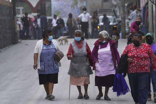 Mujeres caminan ayer por las calles llenas de ceniza en Santiago Xalitzintla, ayer.