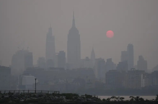 El sol se levanta sobre la silueta al horizonte de la Ciudad de Nueva York en medio de una bruma, en una vista desde Jersey City.