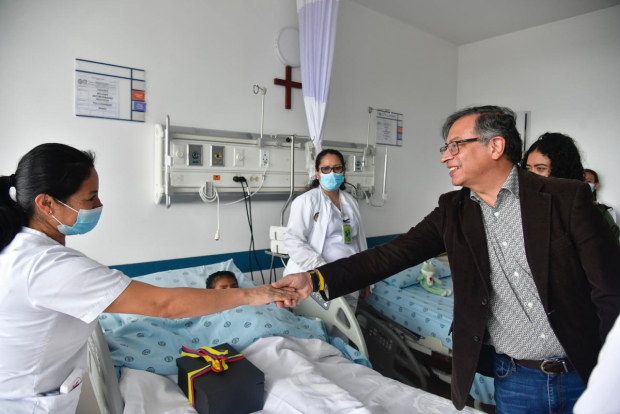 Gustavo Petro, presidente de Colombia, choca la mano con una de las enfermeras mientras uno de los 4 niños rescatados yace en la cama del hospital.