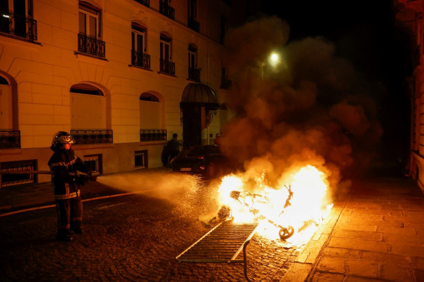 Bombero apaga incendio provocado durante la quinta noche de protestas en Francia.