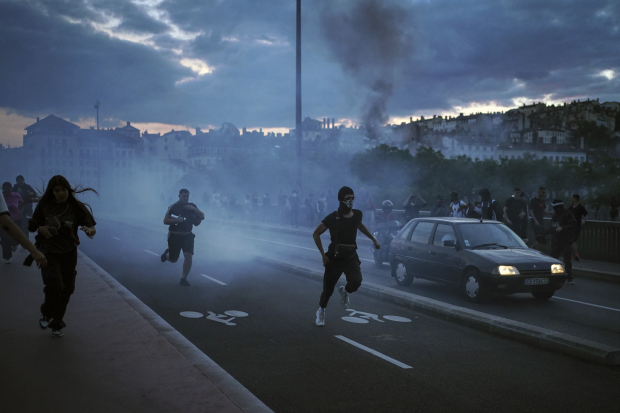 Manifestantes corren mientras los policías de Francia usan gas lacrimógeno en el centro de Lyon, el viernes.