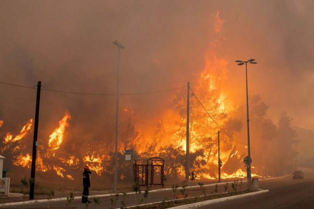 Un bombero junto a las llamas crecientes mientras arde un incendio forestal en el pueblo de Hasia, cerca de Atenas.